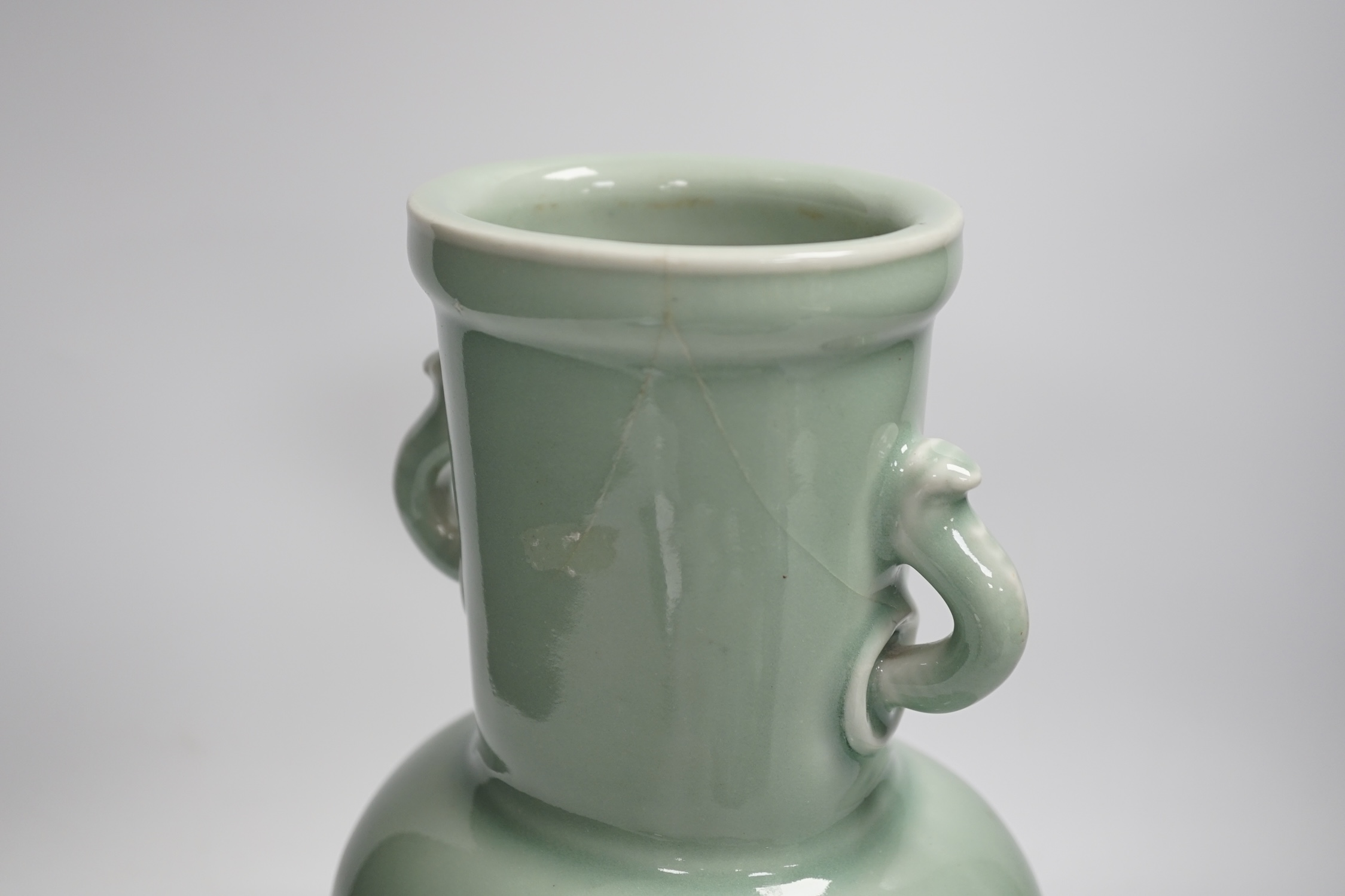 A Chinese celadon glazed two handled vase and a Chinese blue and white vase and dish, celadon vase 28.5cm high. Condition - celadon vase has a firing flaw and large crack, both blue and white vase are in damaged conditio